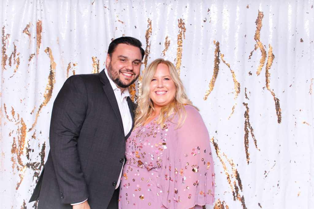 Couple posing in front of a gold and white photo booth backdrop in Tampa